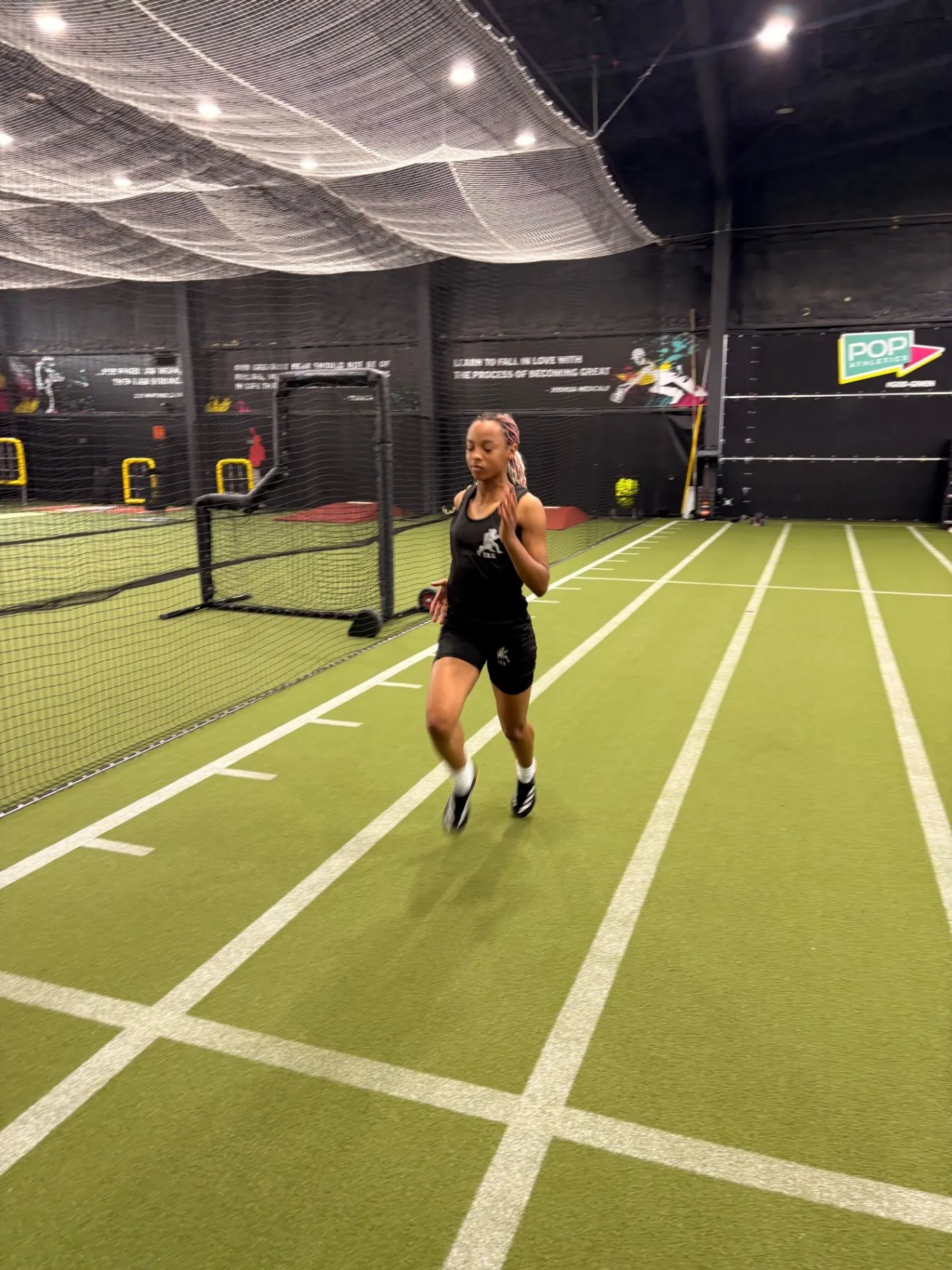 Nailah Belcher running down an indoor training lane in black kit