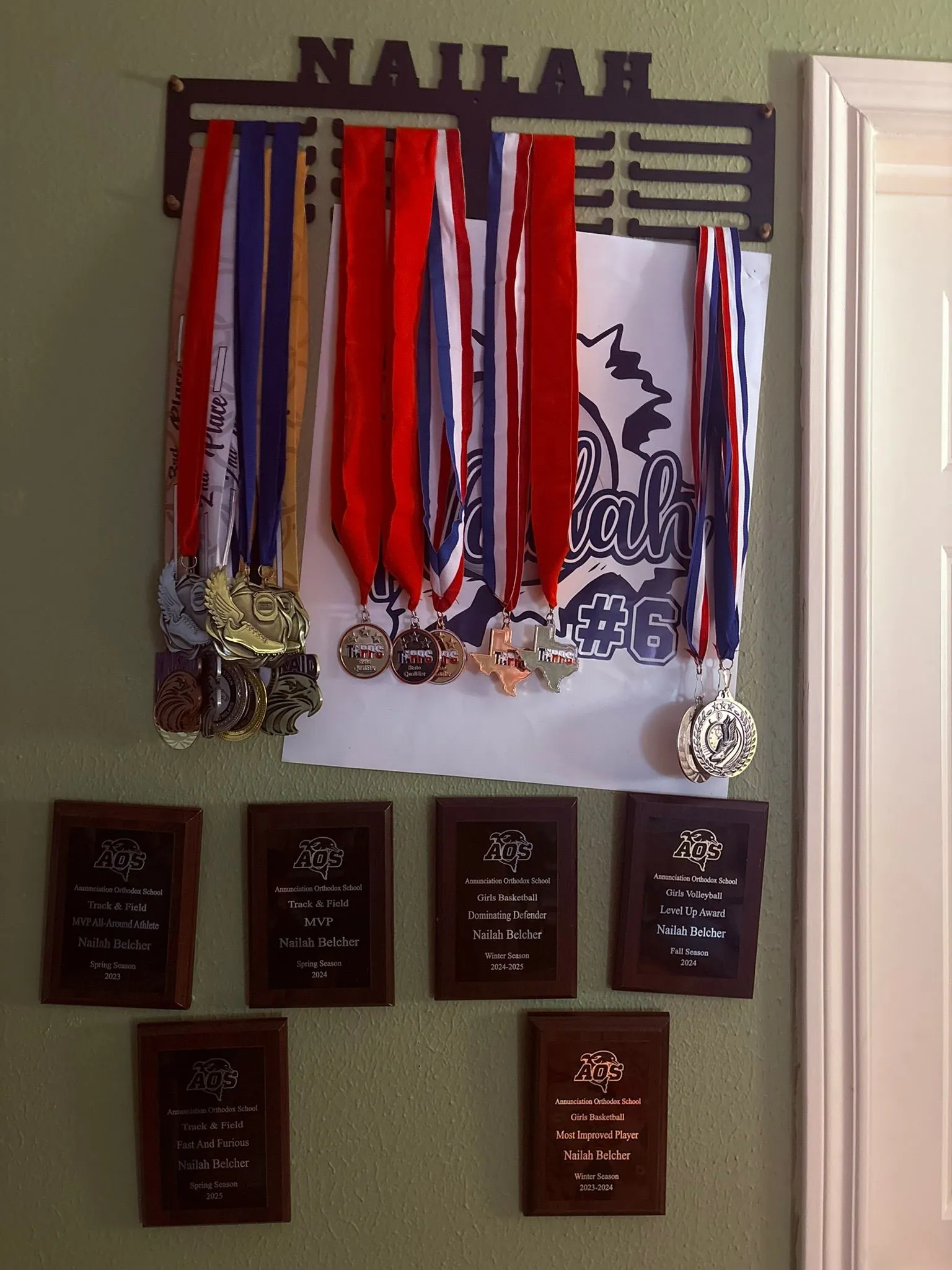 Nailah Belcher's display of track and field, basketball, and volleyball medals and athletic plaques