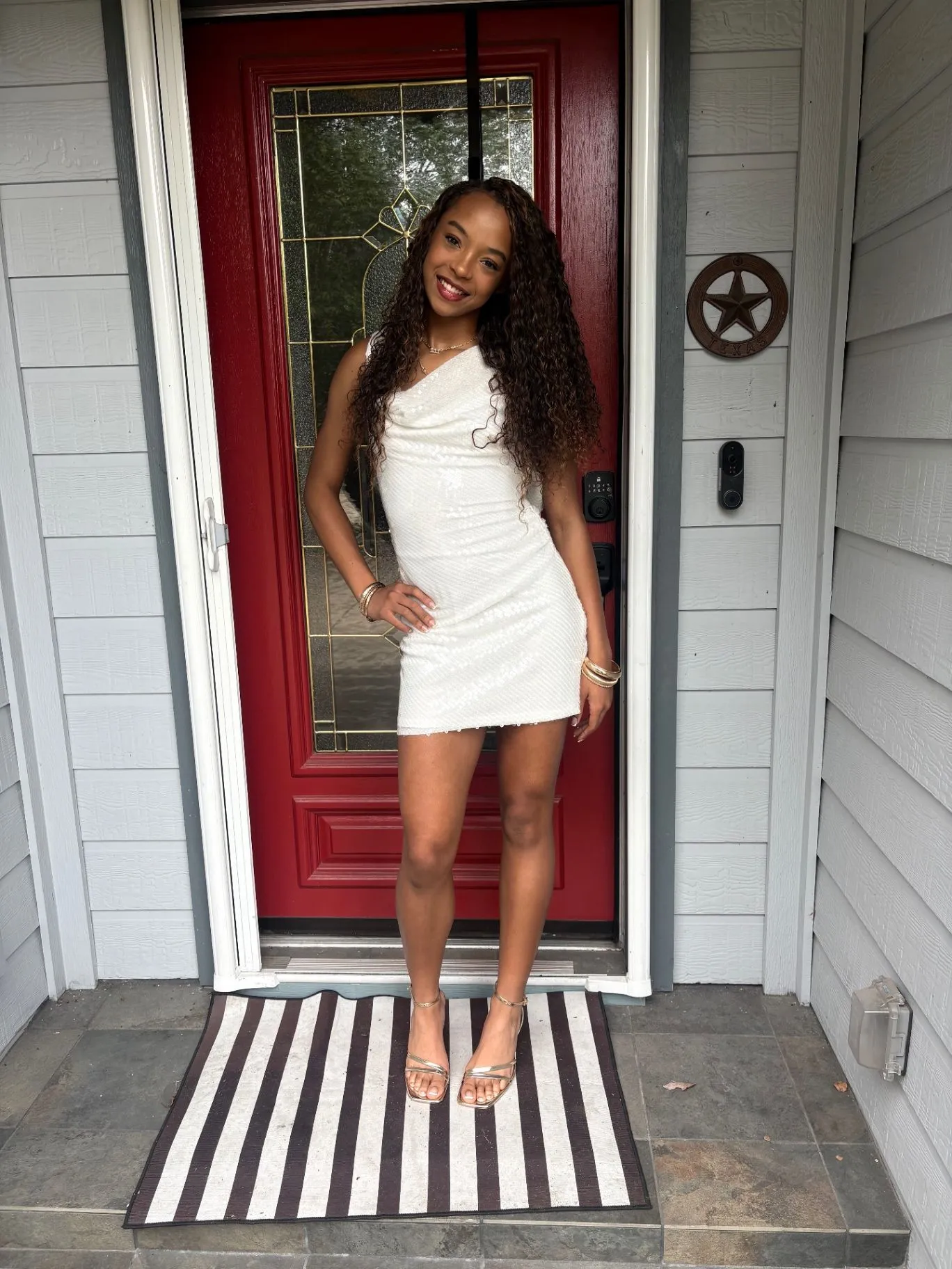 Nailah Belcher smiling in a white dress on her front porch